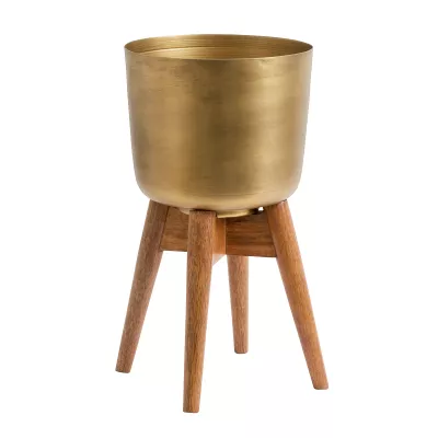 Osłonka Nordal w kolorze antycznego złota na drewnianym stojaku to efektowna dekoracja łącząca elegancję i nowoczesność. Idealna do roślin, suszy i kompozycji dekoracyjnych. Doskonała jako akcent premium w salonie, holu lub sypialni. Ostatnie sztuki dostępne tylko w Kapps Store.